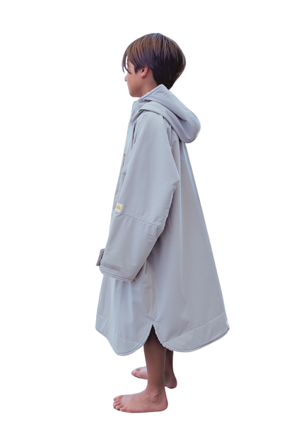 Child wearing a gray hooded changing robe on a white background